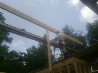 Carpenter setting a ridge beam over a new addition frame — Ice Dam Removal by Roofing Brothers in Hickory Grove