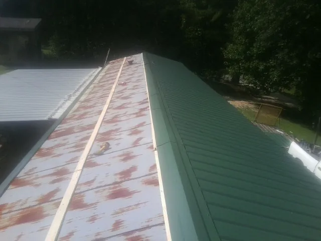 Old rusted panels beside newly installed green metal roofing — Wind Damage Roof Repair by Roofing Brothers in Hickory Grove