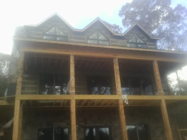 Dormers and porch framing on a large log home under construction — Roof Coating work by our crew in Hickory Grove
