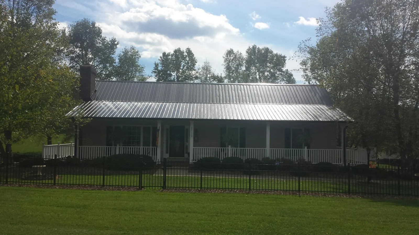 Gray metal roof on a brick ranch with a full width front porch — Gutter Guard Installation work by our crew in Hickory Grove
