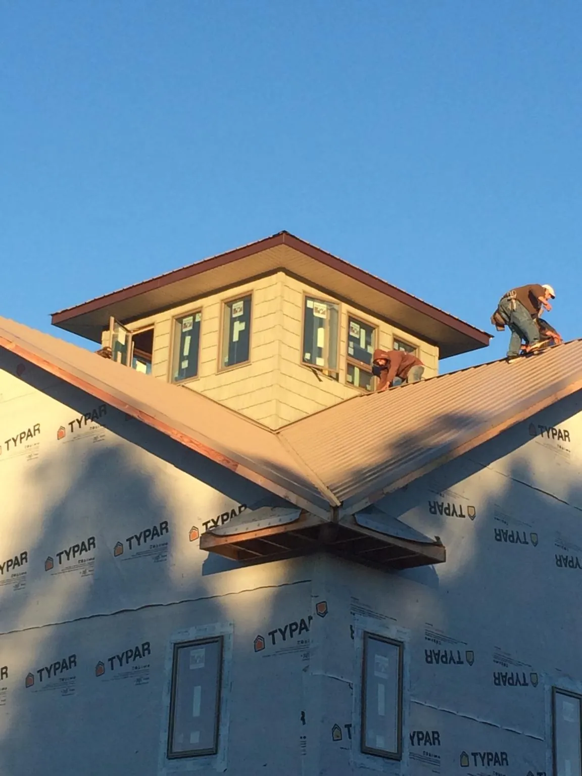 Roofers working around a rooftop cupola on a new metal roof at sunset — Roof Waterproofing in Hickory Grove by Roofing Brothers